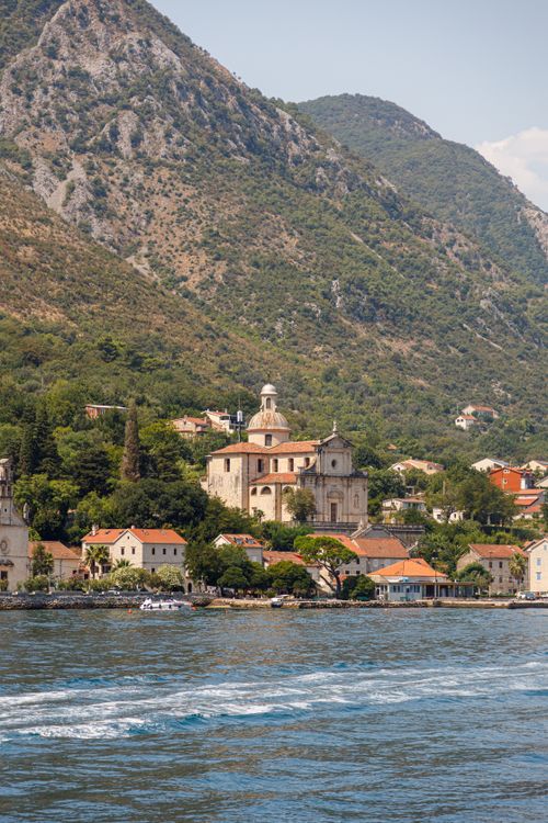 Free Panoramic view of a coastal town featuring a historic church against mountainous backdrop. Stock Photo