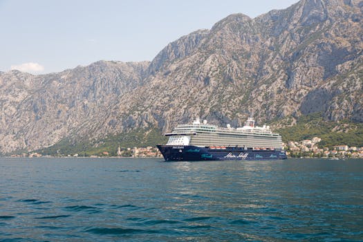 A stunning view of a luxury cruise ship off the coast of Montenegro, with majestic rocky mountains in the backdrop.
