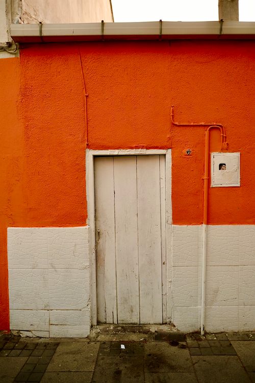 Free A colorful red wall with a rustic wooden door in İzmir captures the essence of urban street design. Stock Photo