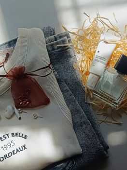 Elegant flat lay of clothing with perfume and skincare products.