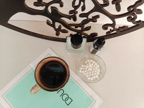 Aesthetic flat lay featuring coffee, pearls, and beauty products on a wooden table.