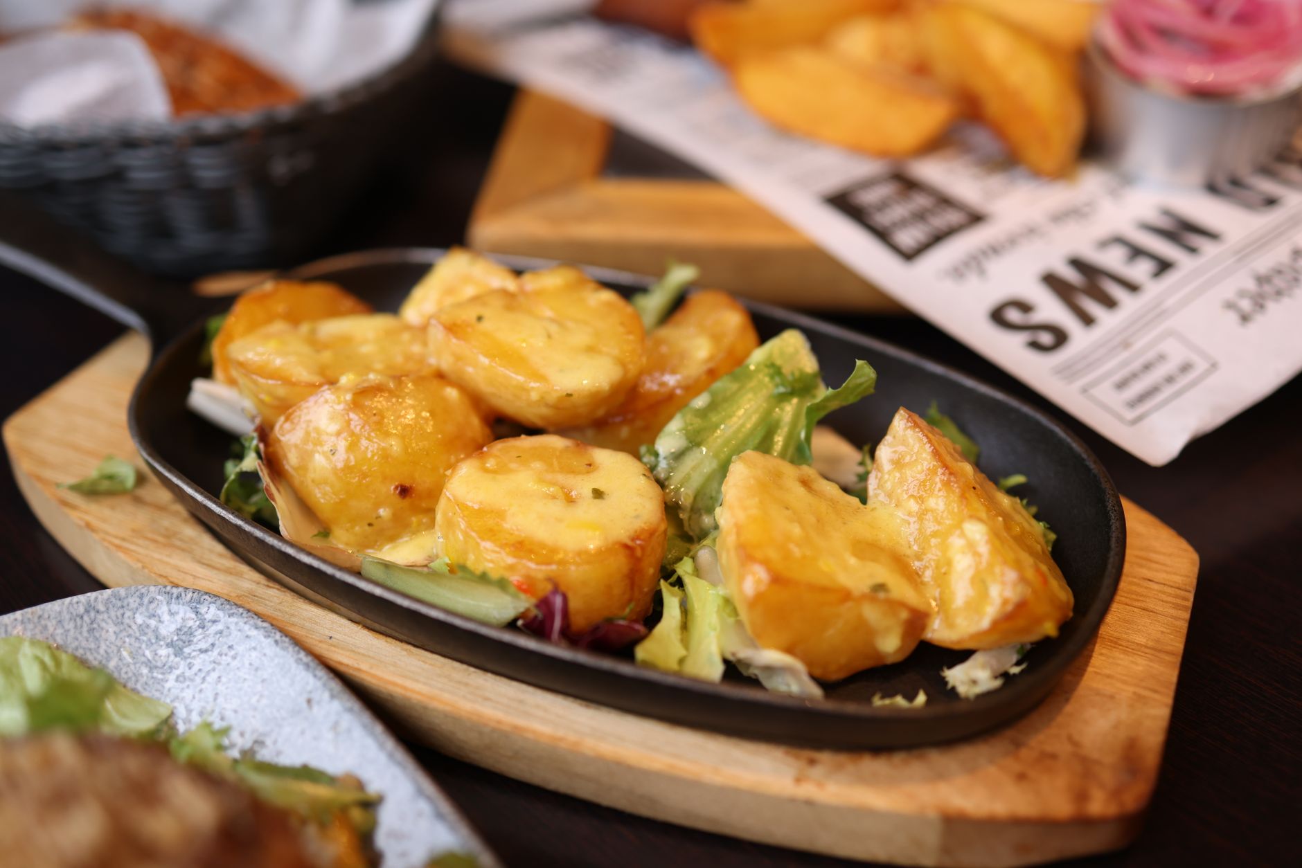 Crispy Hasselback Potatoes: The Ultimate Holiday Side Crispy roasted potatoes on a black skillet, garnished and served with fresh greens.
