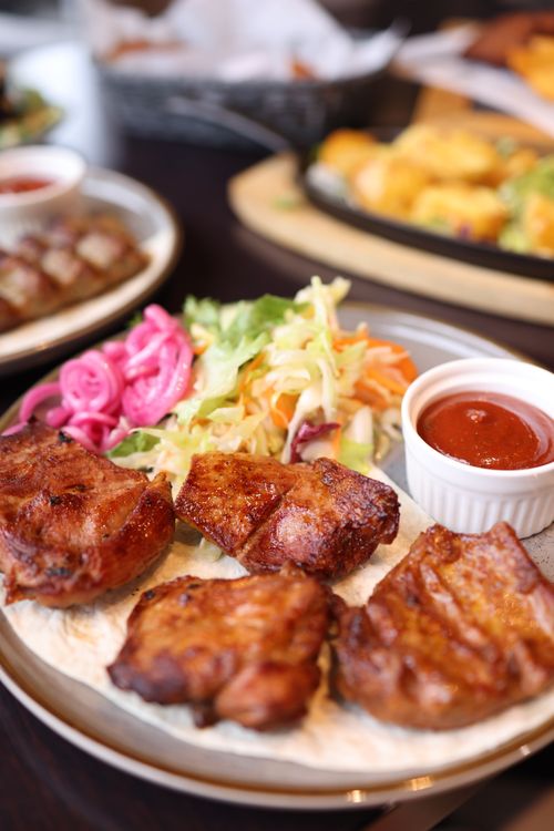 Free Tasty grilled meat served with coleslaw and sauce on a dining table for a perfect meal. Stock Photo