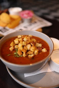 Warm tomato soup served with crispy croutons in a stylish bowl.