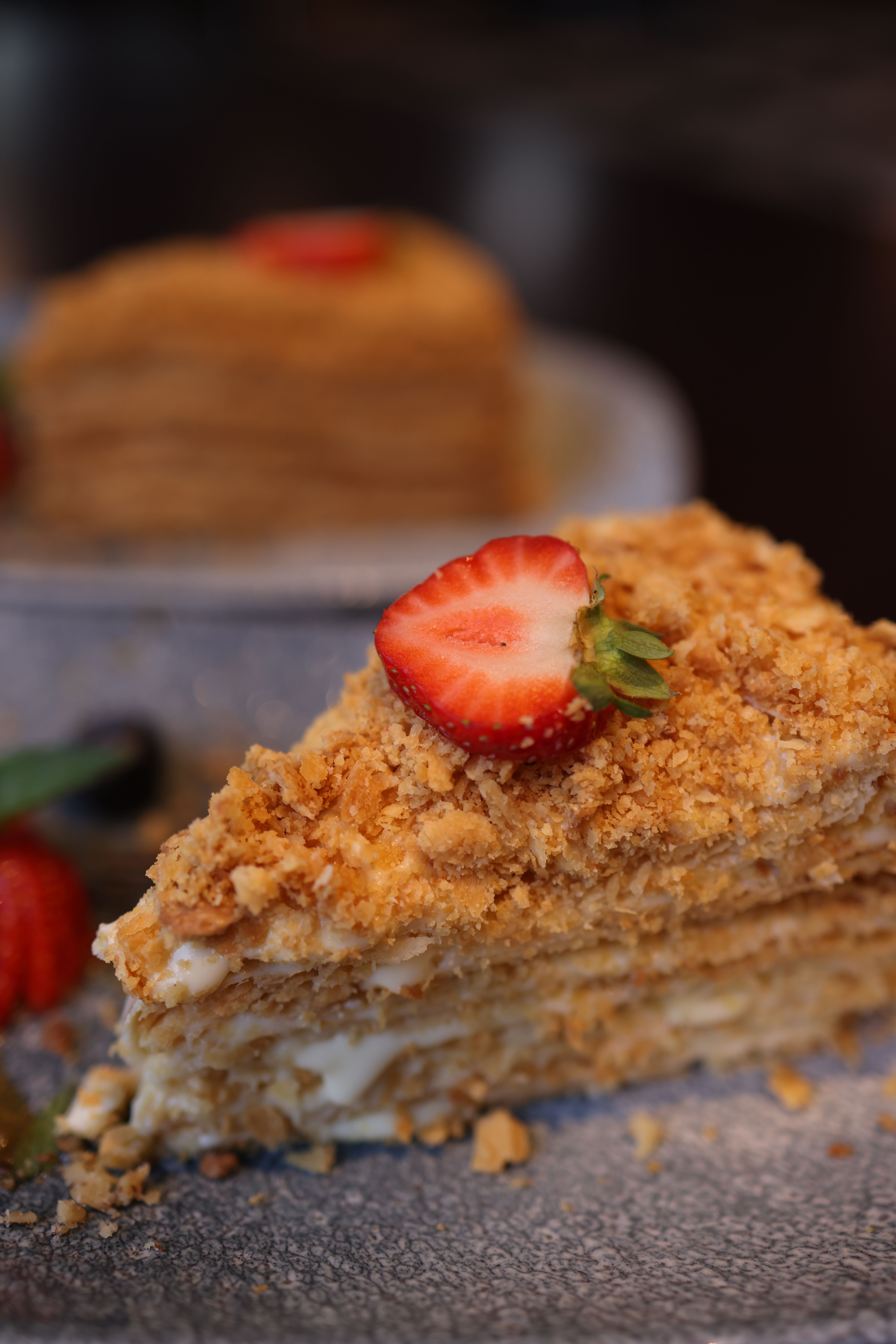Scrumptious layered cake slice garnished with fresh strawberry.