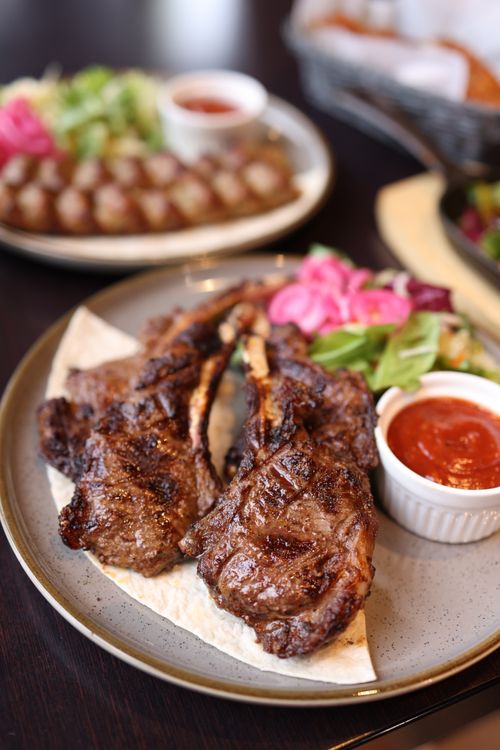 Free Juicy grilled lamb chops served with fresh salad and spicy sauce on a rustic plate. Stock Photo