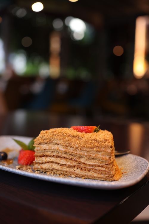 Free Mouthwatering layered cake dessert topped with fresh strawberries in a cozy cafe setting. Stock Photo