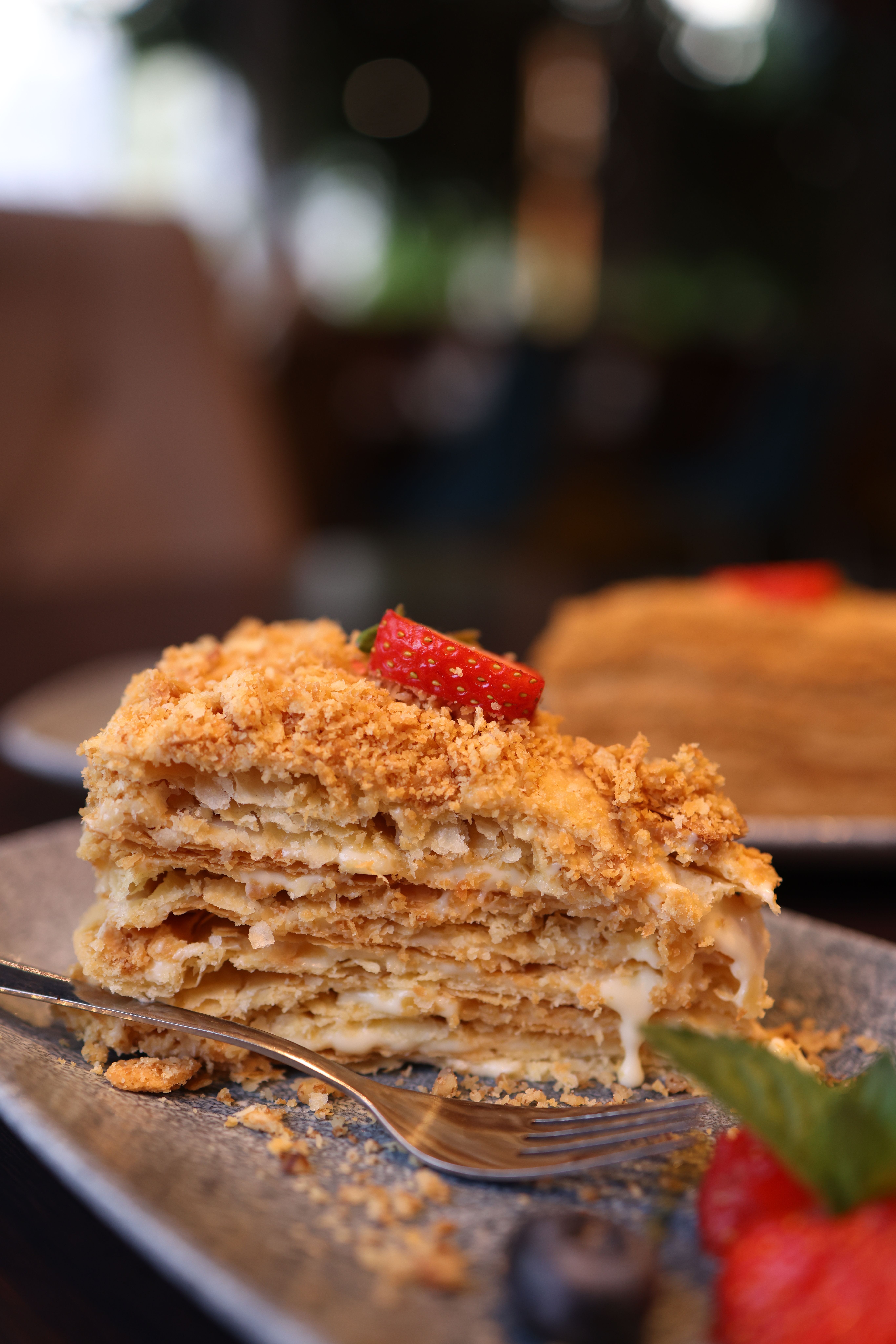 Slice of Napoleons cake with fresh strawberries and crumb topping on plate.