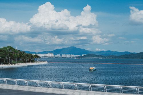 Free Peaceful waterfront scene with boat, mountains, and dramatic sky. Stock Photo