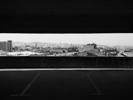 Monochrome view from a parking lot overlooking an urban skyline.