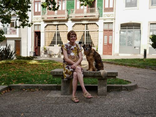 Free Elderly woman with dog sitting on a bench in a charming park setting. Stock Photo