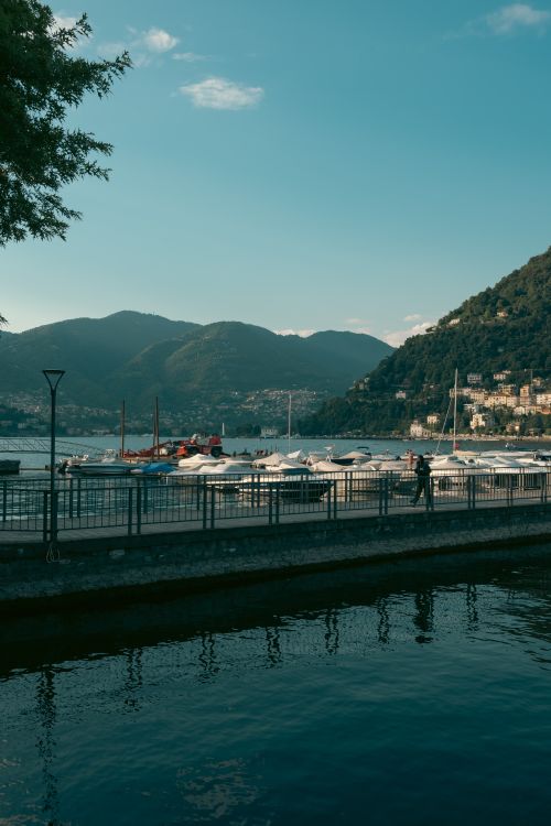 Free A picturesque view of boats moored along Lake Como with mountainous backdrop in Italy. Stock Photo