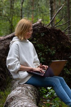 Young woman working on a laptop outdoors, enjoying nature.