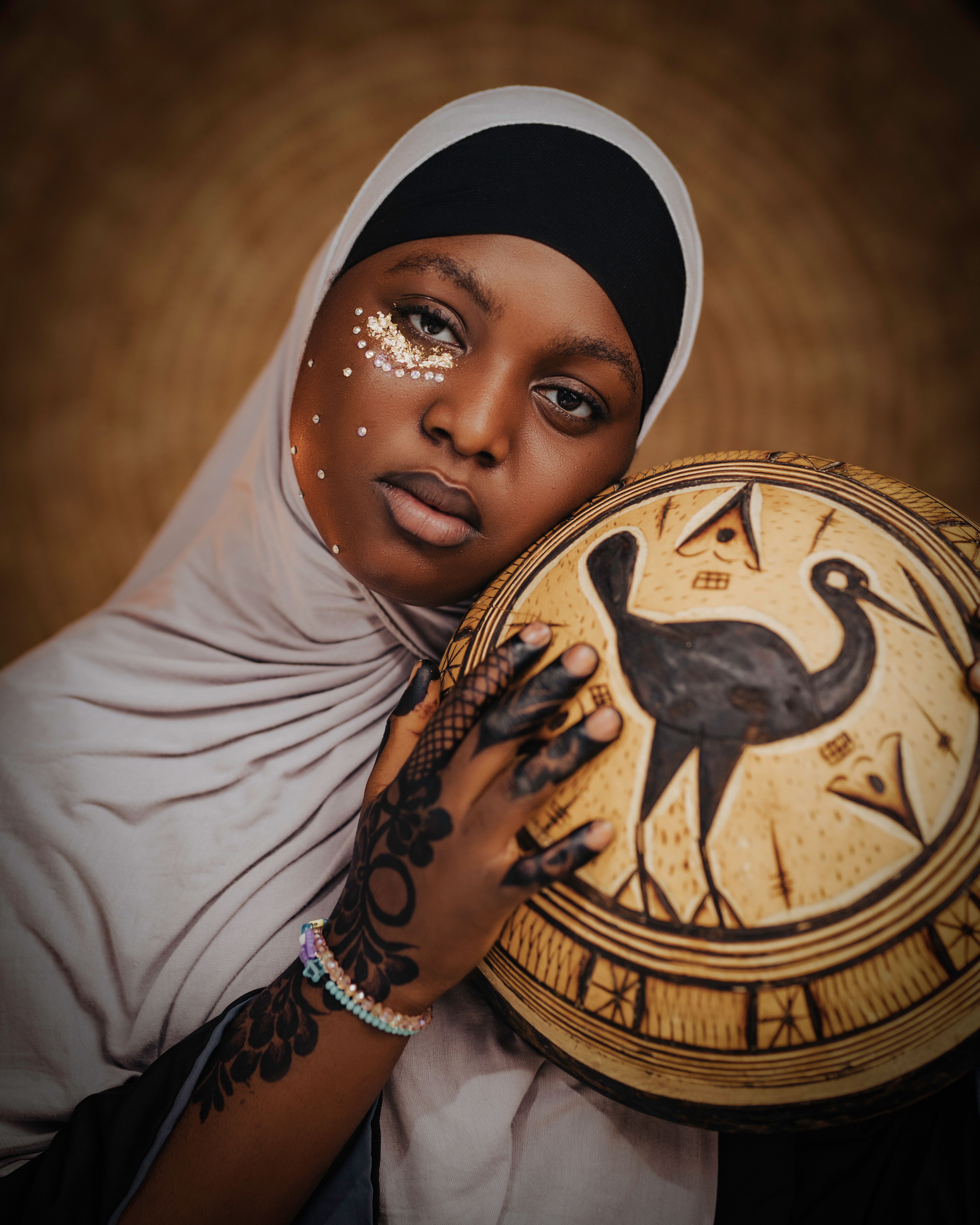 African woman holding tribal decor, showcasing cultural beauty and artistry.
