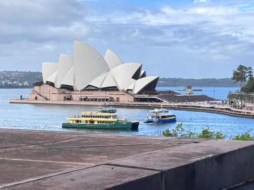 Free Iconic Sydney Opera House with ferries on a calm harbor under a clear sky. Stock Photo