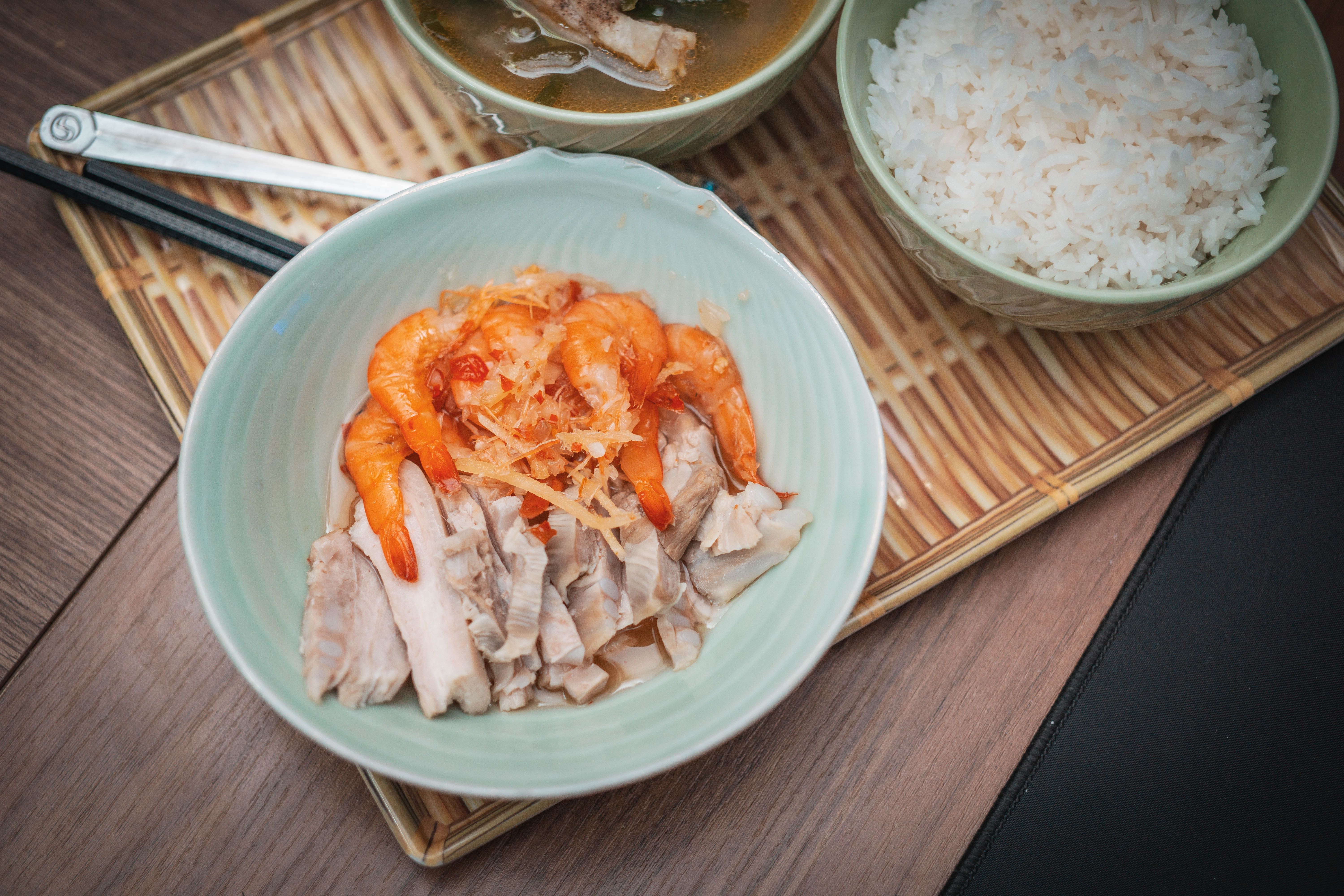 Delicious Asian seafood meal featuring shrimp, pork, rice, and soup presented in elegant green bowls.