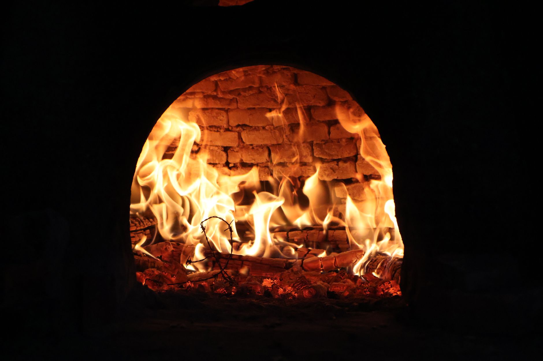 Captivating image of a roaring fire inside a traditional wood-fired oven, exuding warmth and rustic charm