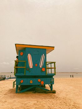 Vibrant blue lifeguard hut on a sandy beach with decorative surfboards, perfect for summer vibes.