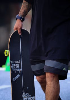 Close-up of a skateboarder holding a board in an urban setting, showcasing street style and athleticism.