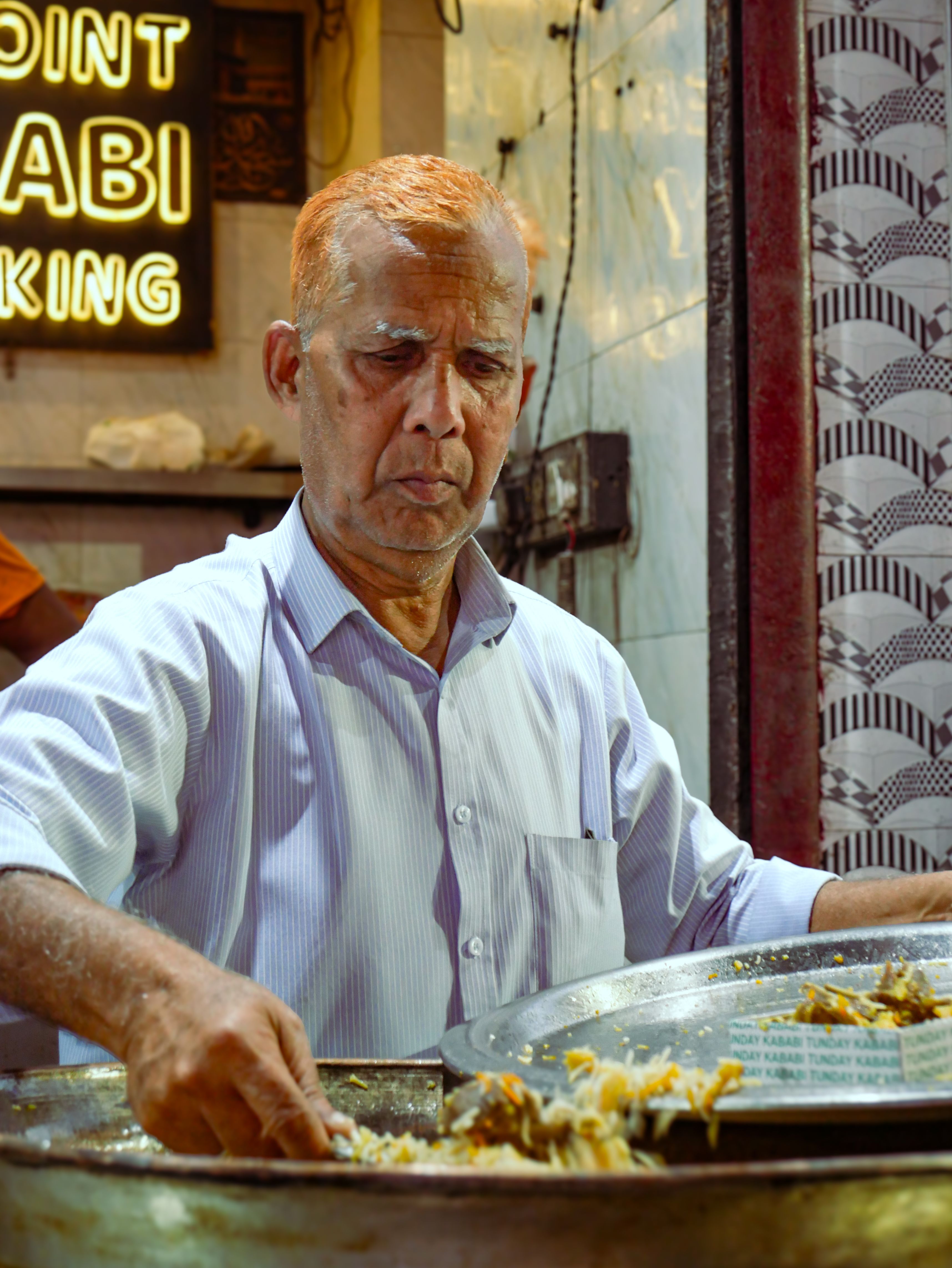An Indian street vendor preparing and serving traditional food at a market stall.