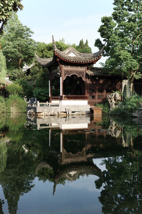 Free Tranquil scene of a Chinese garden pavilion reflected in a calm pond. Stock Photo