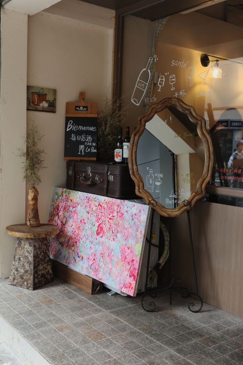 Free A welcoming cafe entrance with artistic elements and vintage decor, featuring a colorful painting and antique mirror. Stock Photo