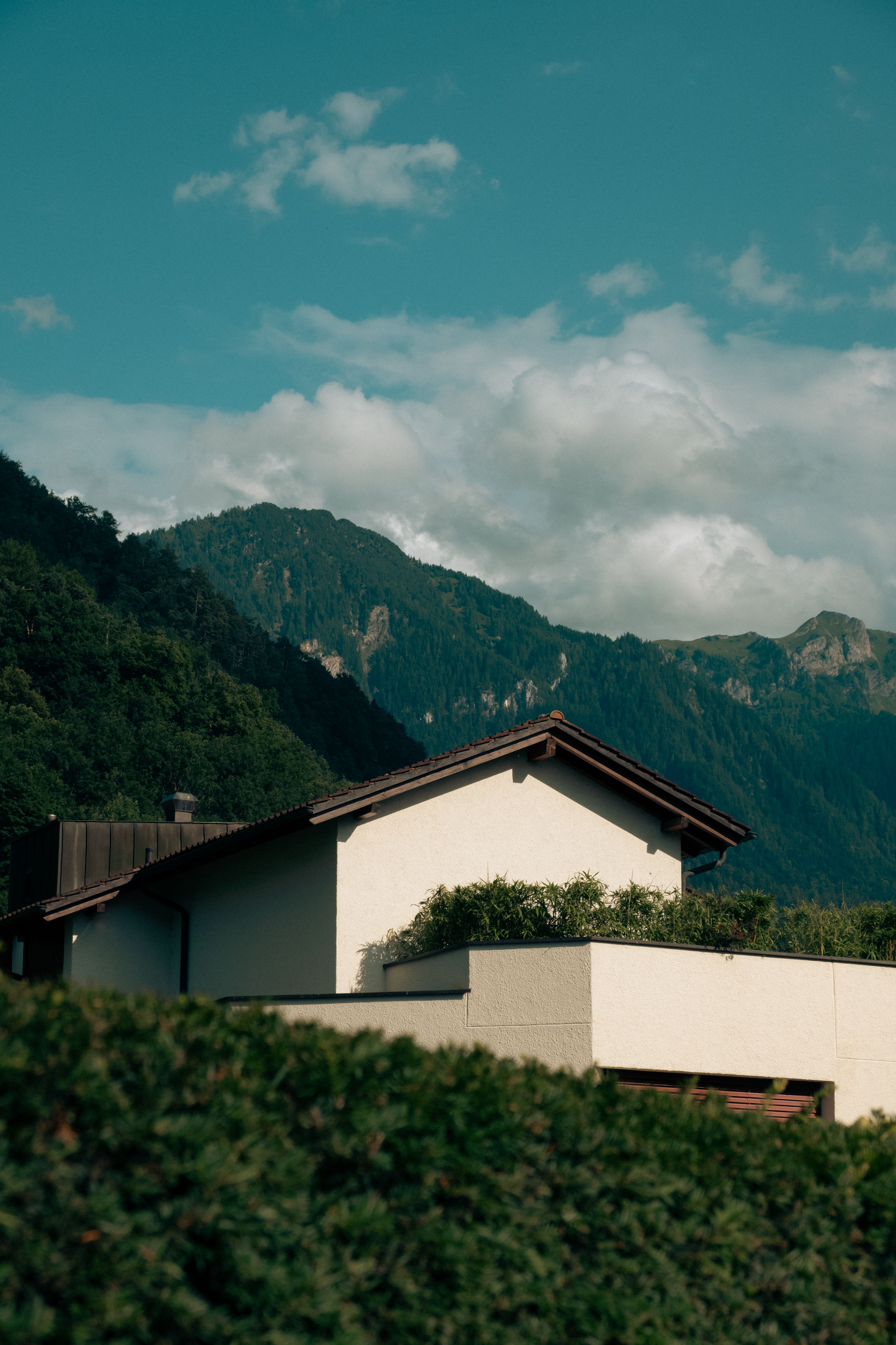 A contemporary mountain home with a standing-seam metal roof and alpine backdrop
