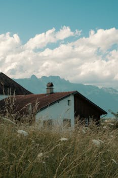 Charming alpine house in Switzerland with a breathtaking view of the mountains and clear summer skies.