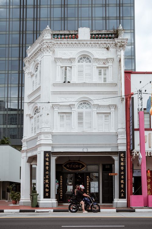 Free A historic white building with intricate details and motorbike passing by in a modern urban setting. Stock Photo