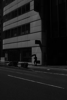 Dramatic urban street scene with person silhouetted by building shadows
