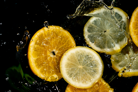 Vibrant lemon and orange slices splashing in water, capturing freshness.