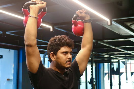 Focused man lifts kettlebells during an indoor workout session in a modern gym.
