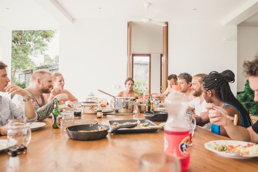 A diverse group of adults enjoying a meal together at a table in Bali, Indonesia.