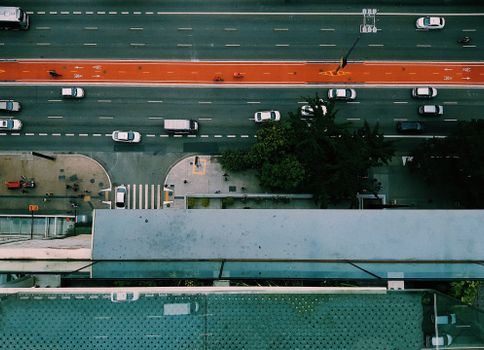 Aerial shot of an urban road with vehicles, bike lane, and pedestrians, captured from above.