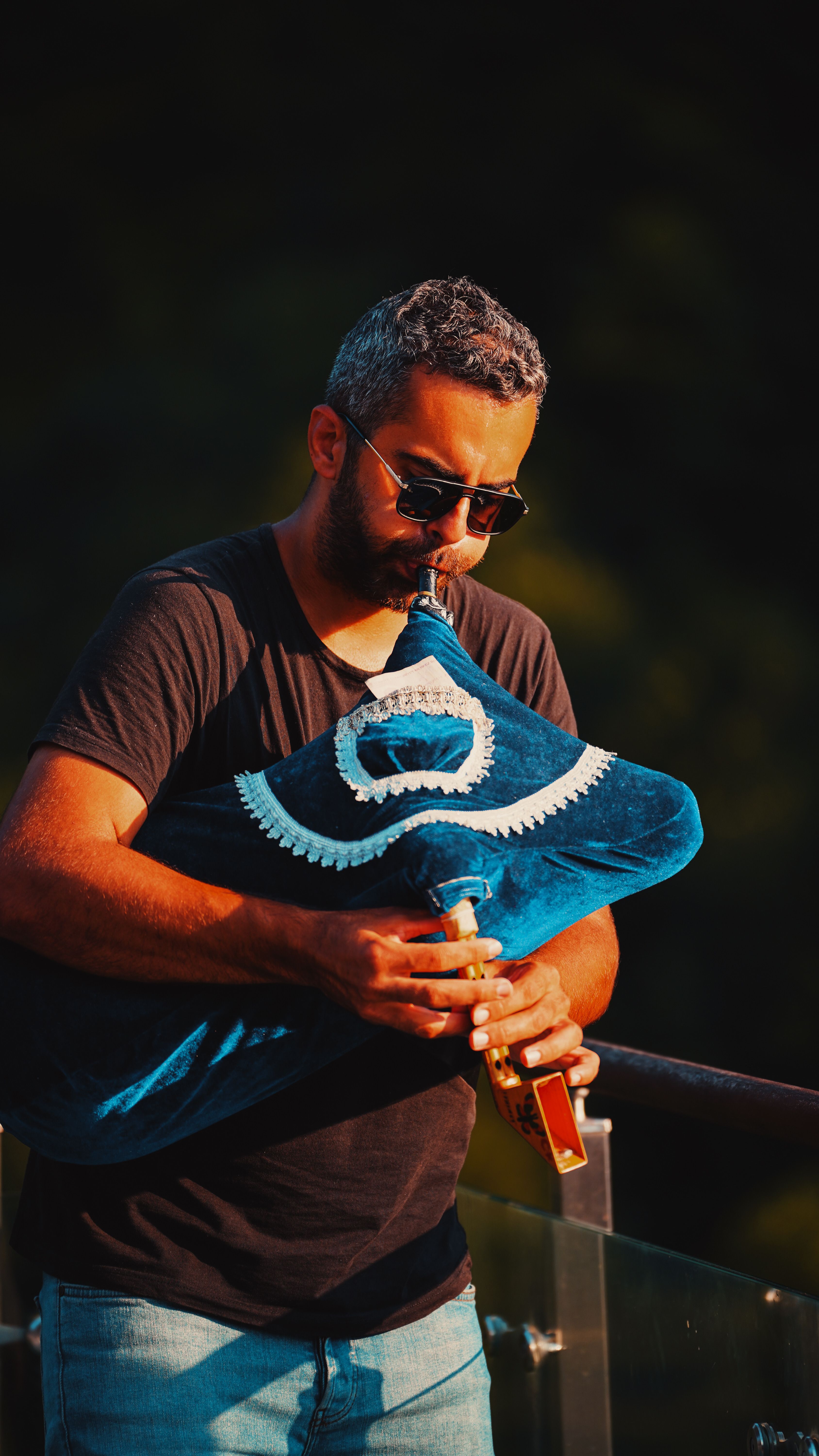 A man skillfully playing a traditional blue bagpipe in an outdoor setting.