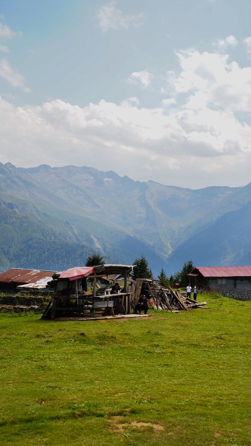 Free Tranquil mountain landscape featuring rustic cabins amidst lush greenery, under a clear sky. Stock Photo