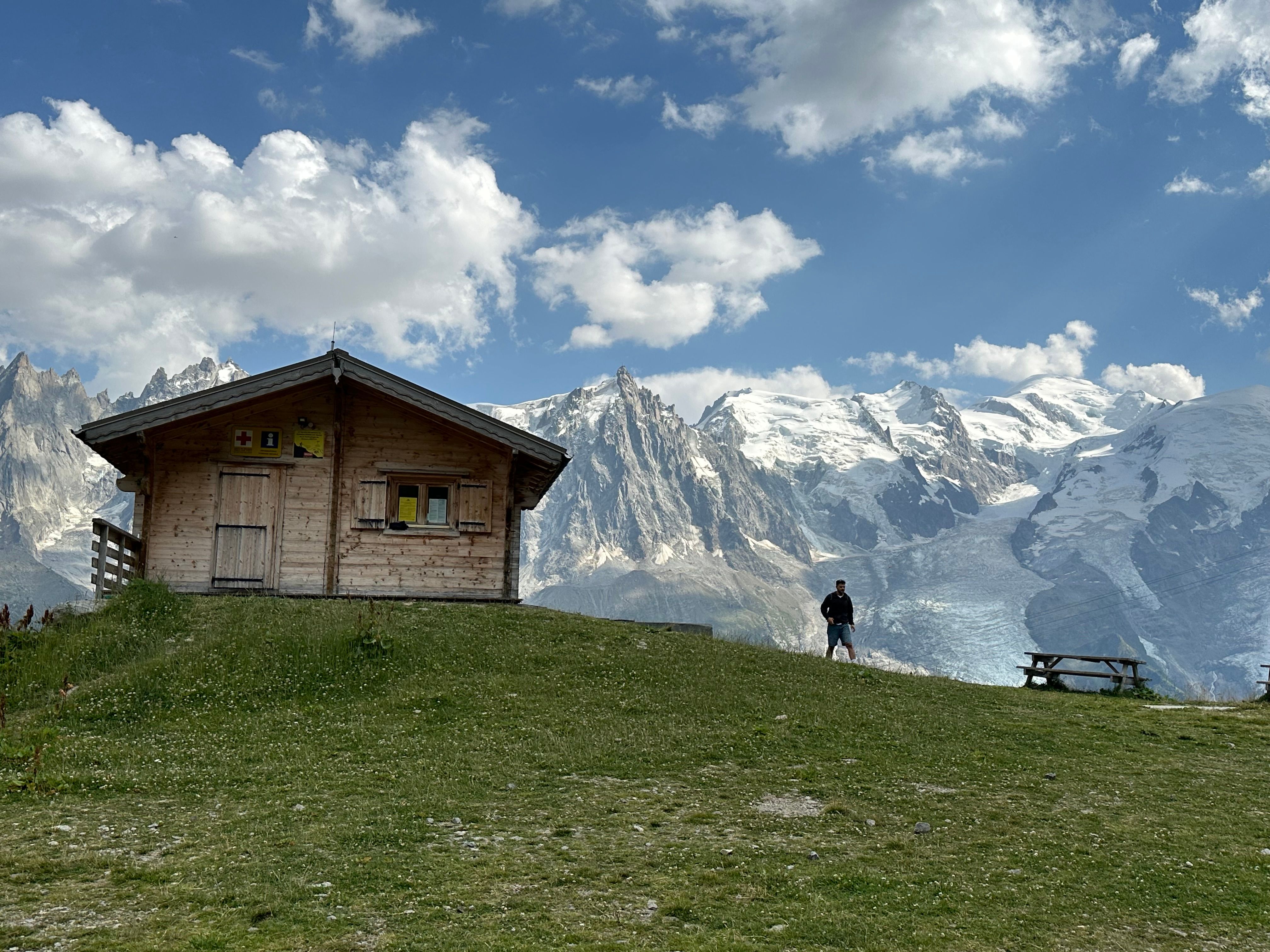 A rustic wooden chalet with Mont Blanc backdrop in Chamonix, France, against a clear blue sky.