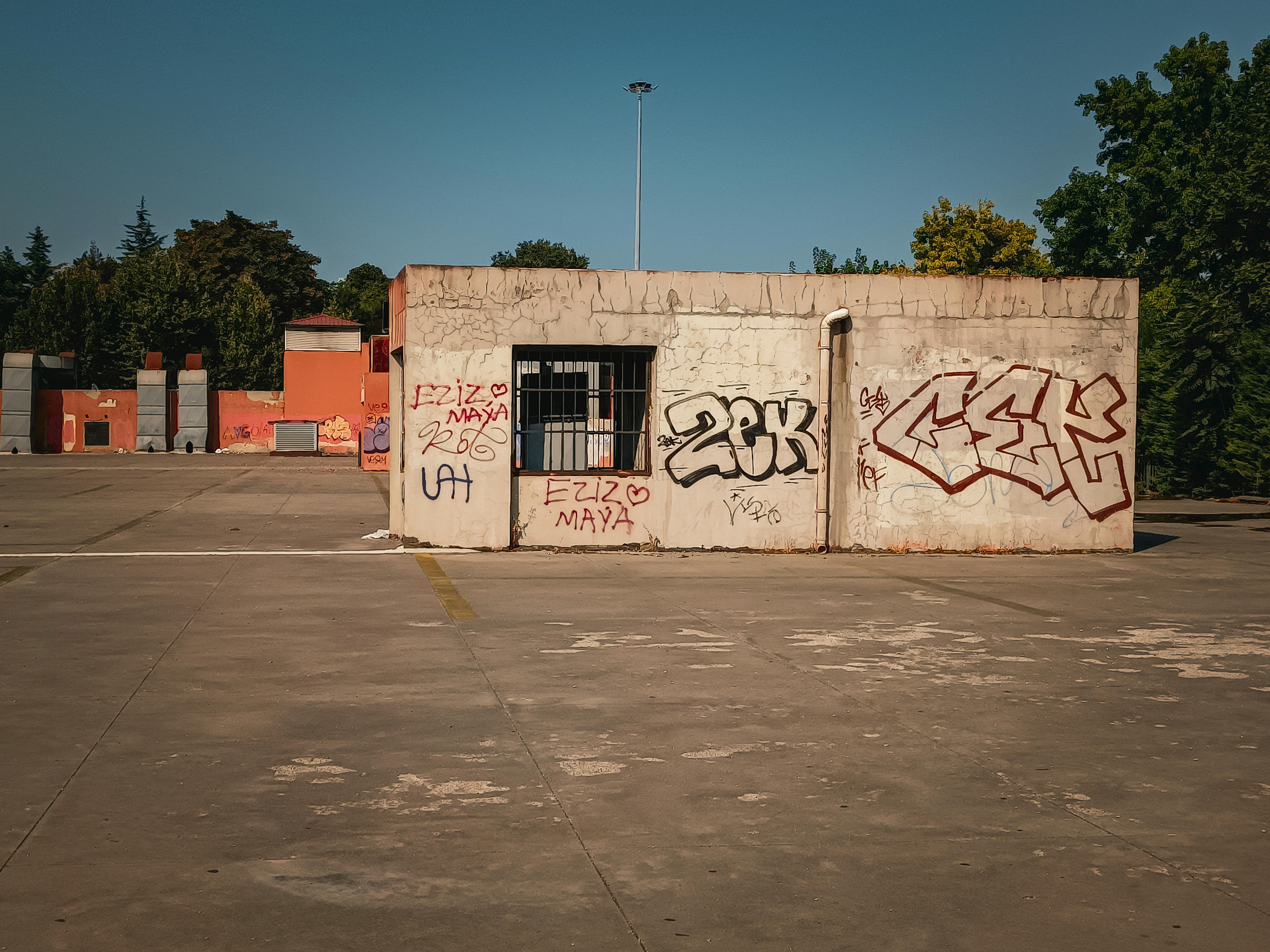 Free A lone concrete structure with vibrant graffiti in an urban environment under a clear blue sky. Stock Photo