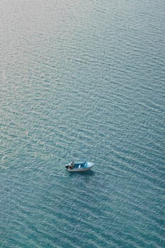 A lone person rowing a small boat on serene blue waters in Kabul, Afghanistan. Perfect for minimalistic themes.