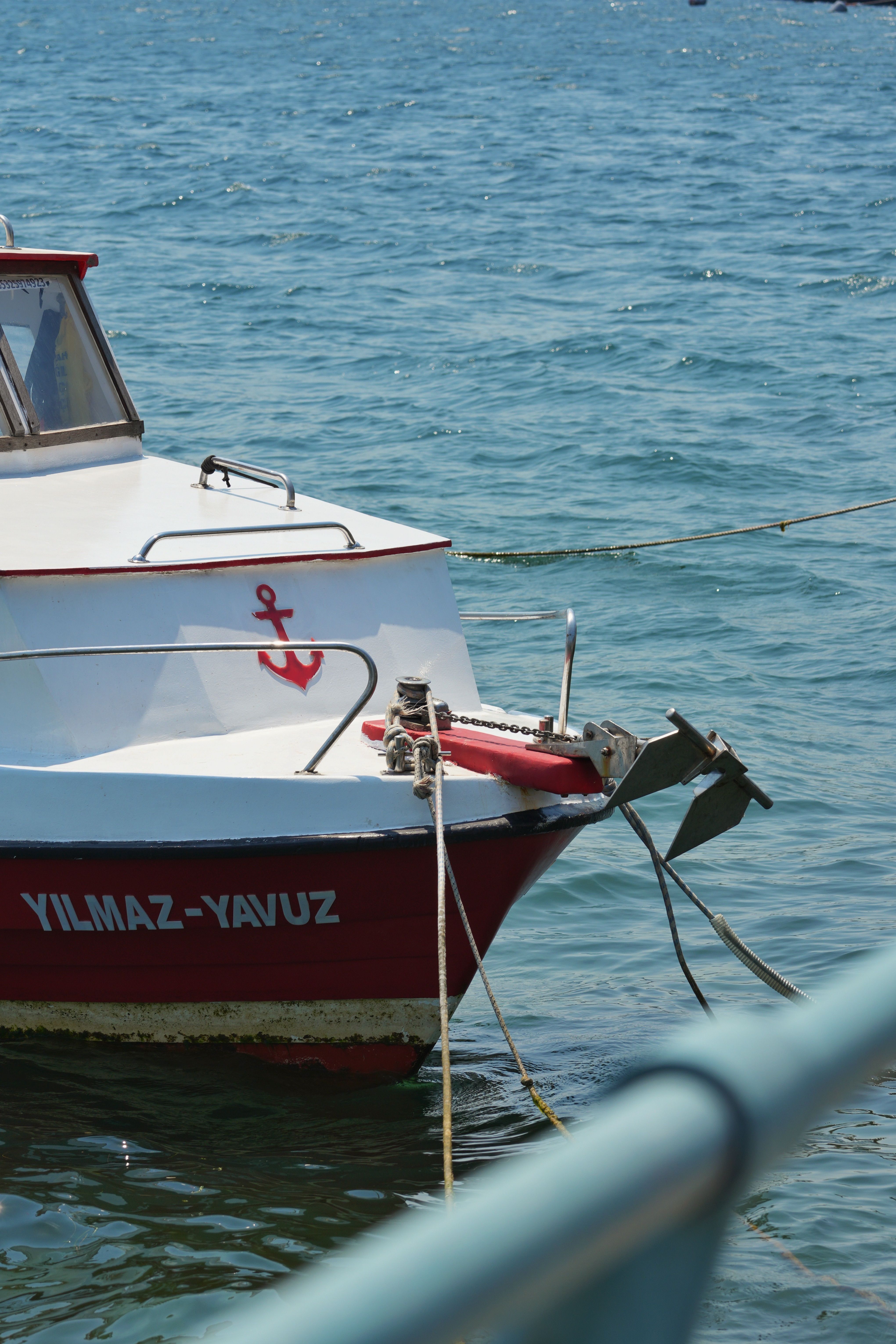 Close-up of a red and white boat named Yilmaz-Yavuz docked in the blue waters of İstanbul, Türkiye.