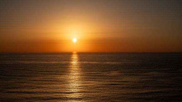 Beautiful golden sunset over the Atlantic Ocean in Portugal, casting a warm glow on the water.