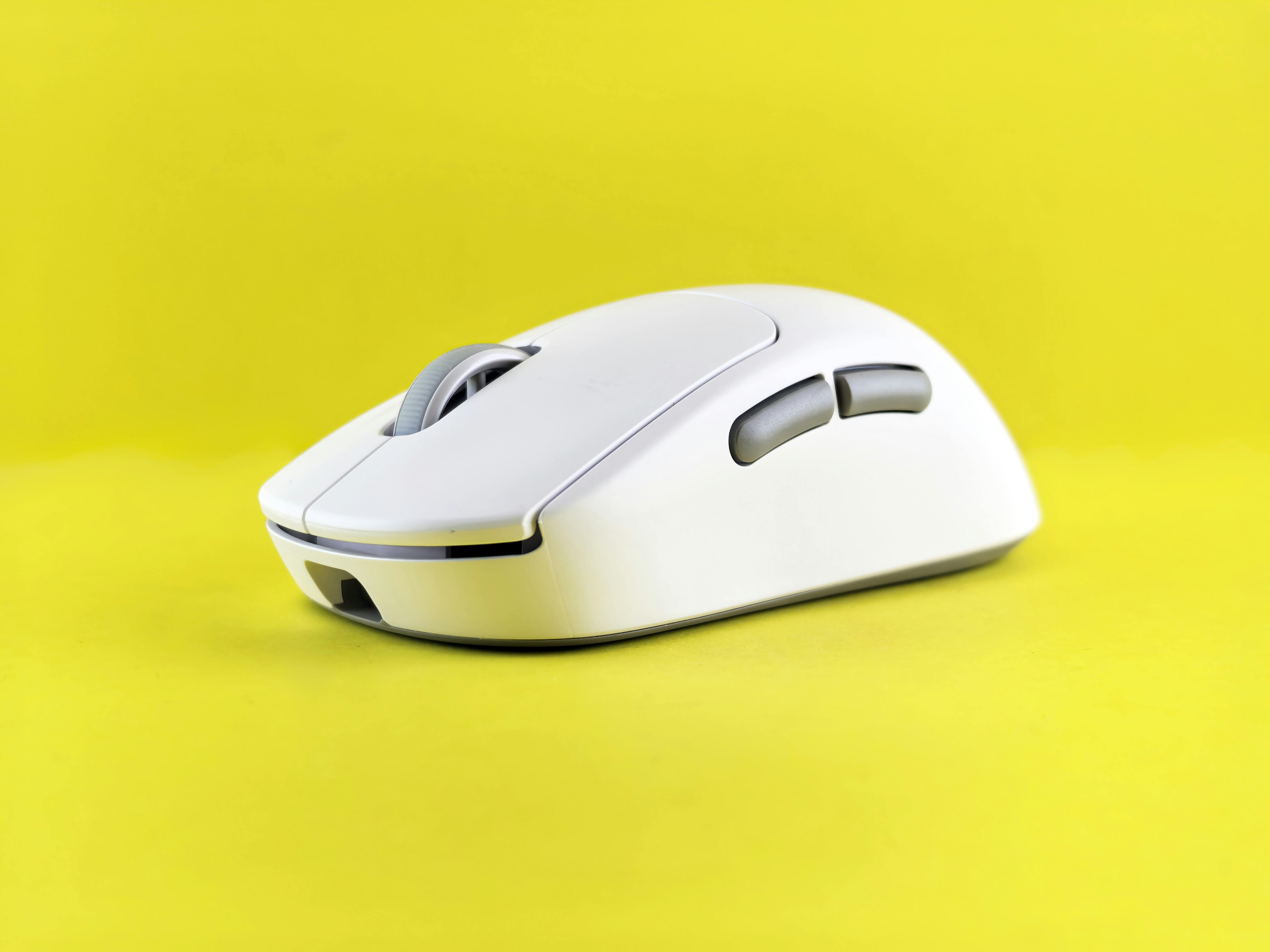 Modern white wireless mouse against a bright yellow backdrop, emphasizing technology and design.