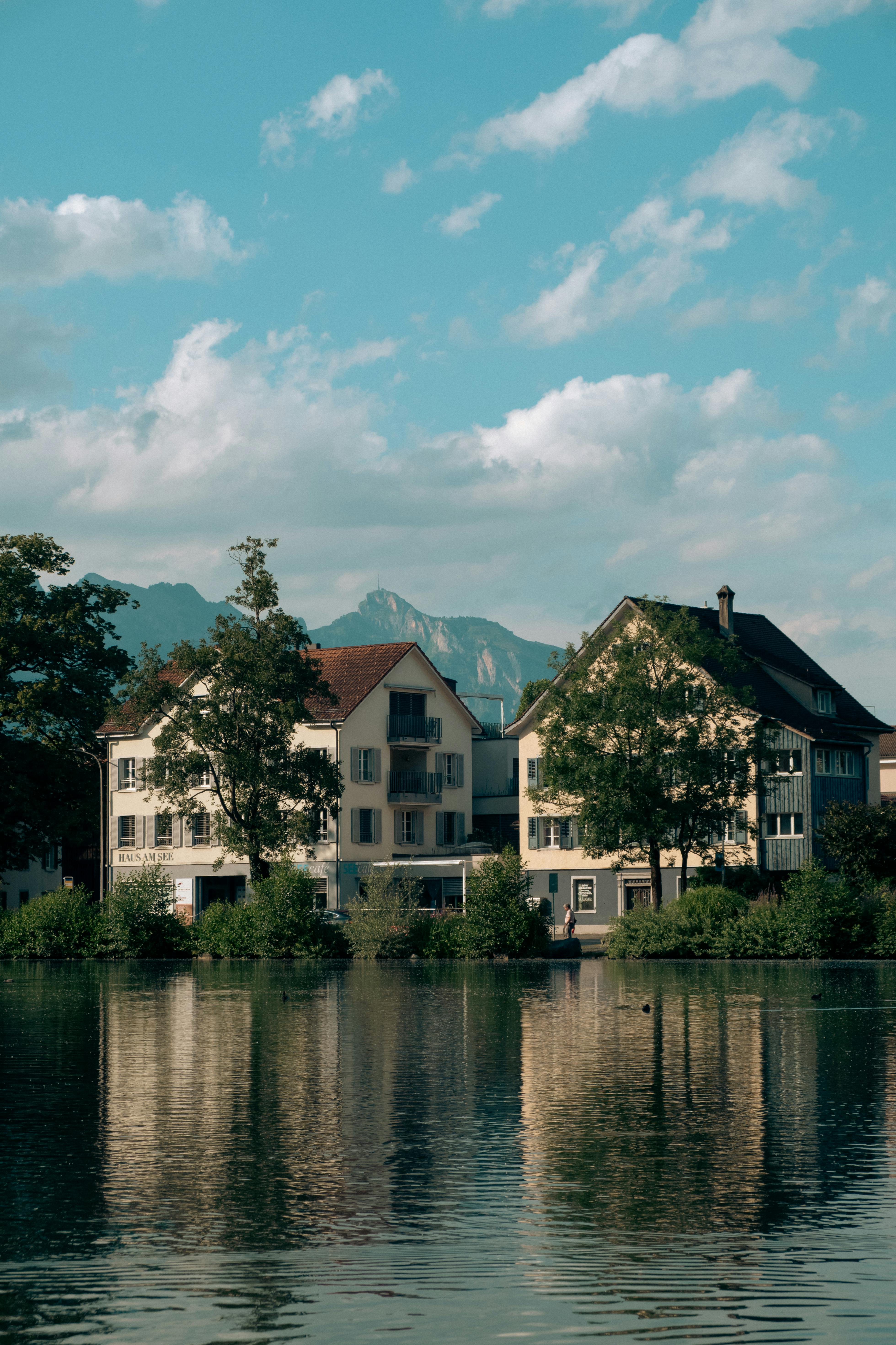 Picturesque Swiss houses by a tranquil lake with alpine mountains in the background during summer.
