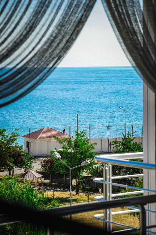 Free A picturesque ocean view framed by curtains from a modern balcony. Stock Photo