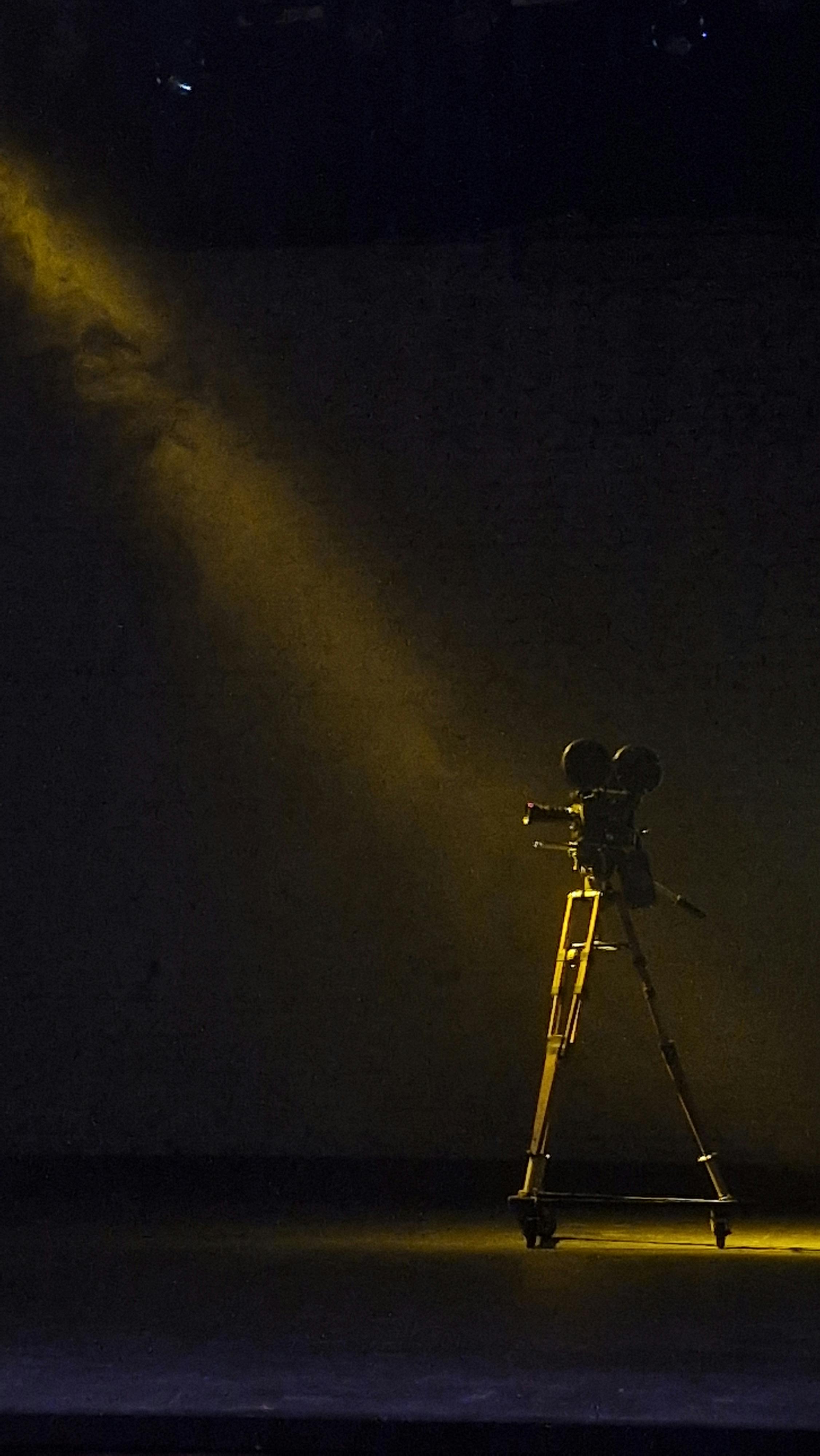 Free A single vintage film camera is illuminated by a spotlight on a dark stage. Stock Photo