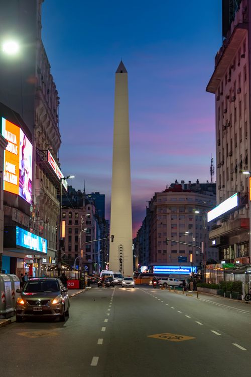 Free The Obelisk of Buenos Aires against a vibrant dusk sky, surrounded by urban city life. Stock Photo