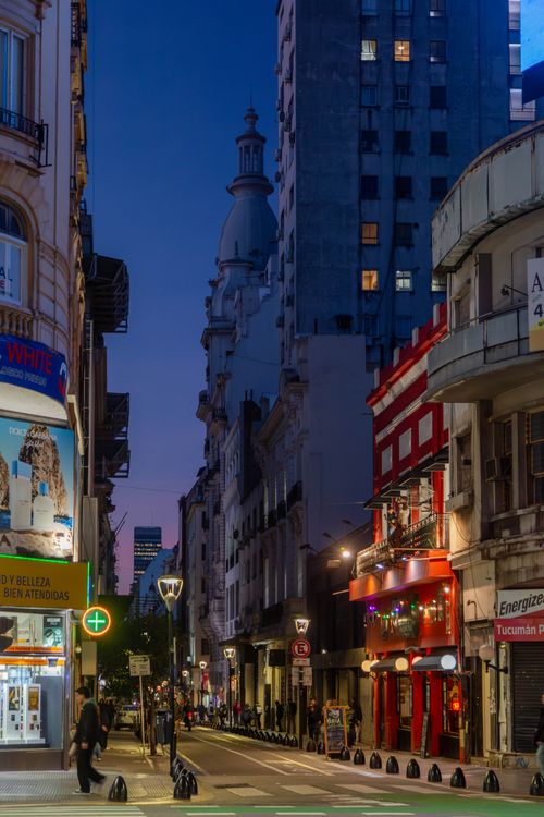 Free Vibrant downtown Buenos Aires street at dusk with illuminated buildings and lively atmosphere. Stock Photo