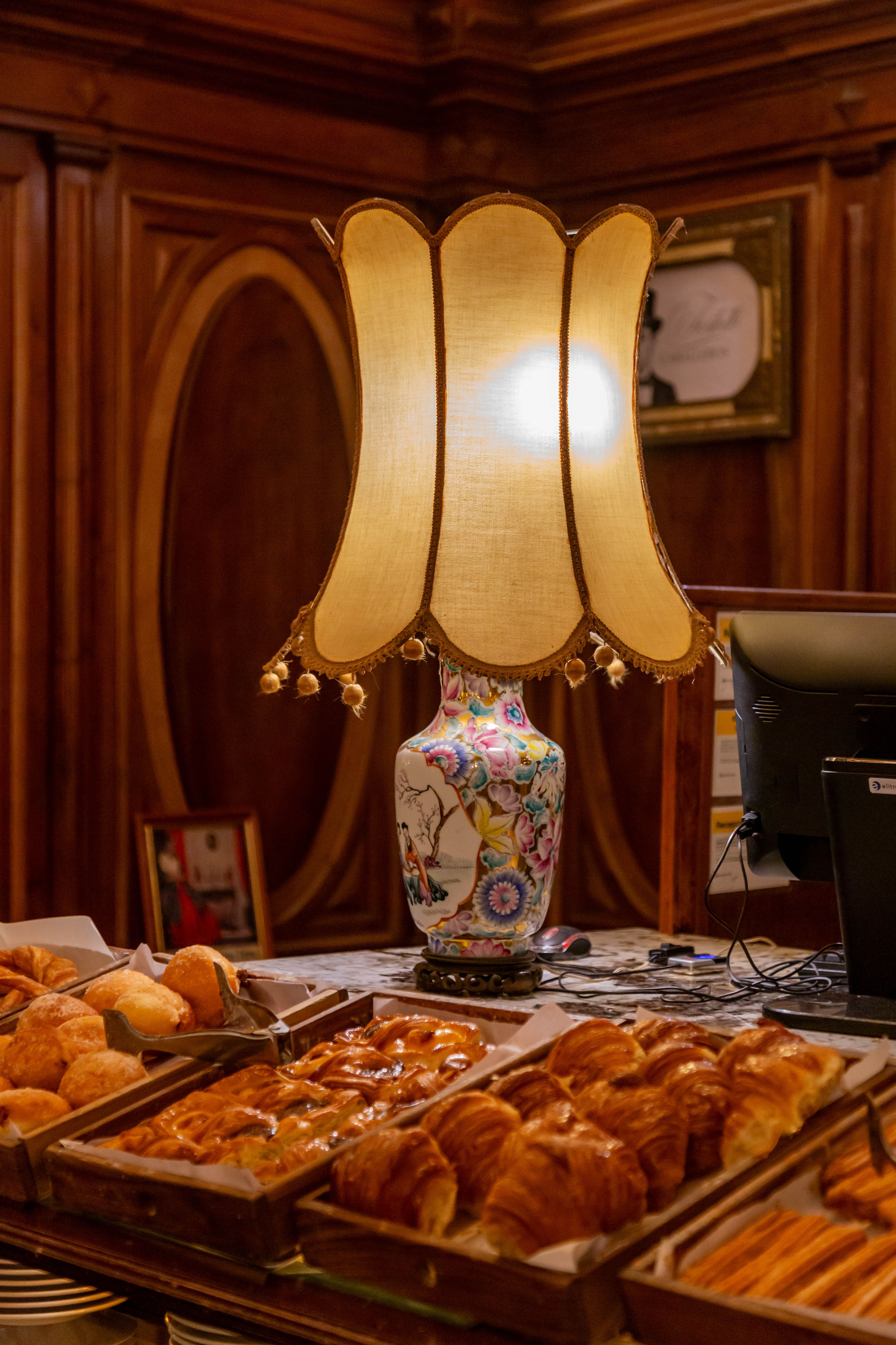 Warm interior of a Buenos Aires cafe with a vintage table lamp illuminating fresh pastries.