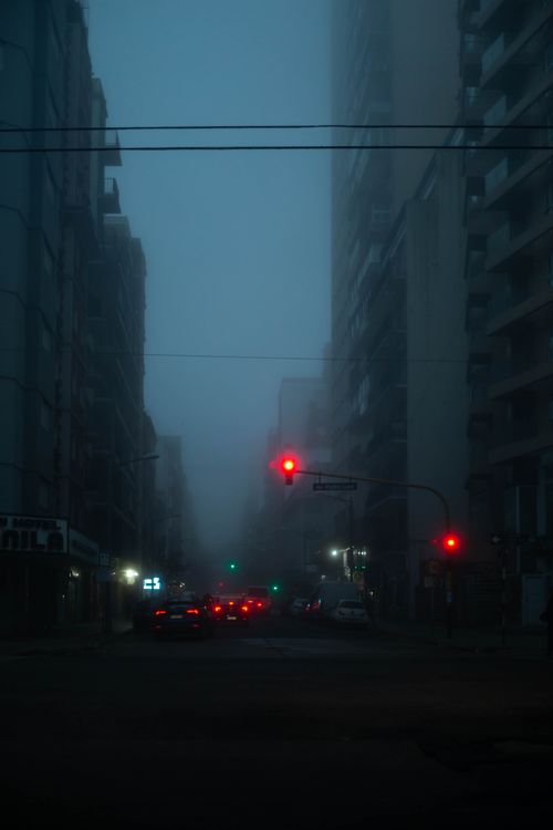 Free Foggy night street scene in Buenos Aires with glowing traffic lights and tall buildings. Stock Photo