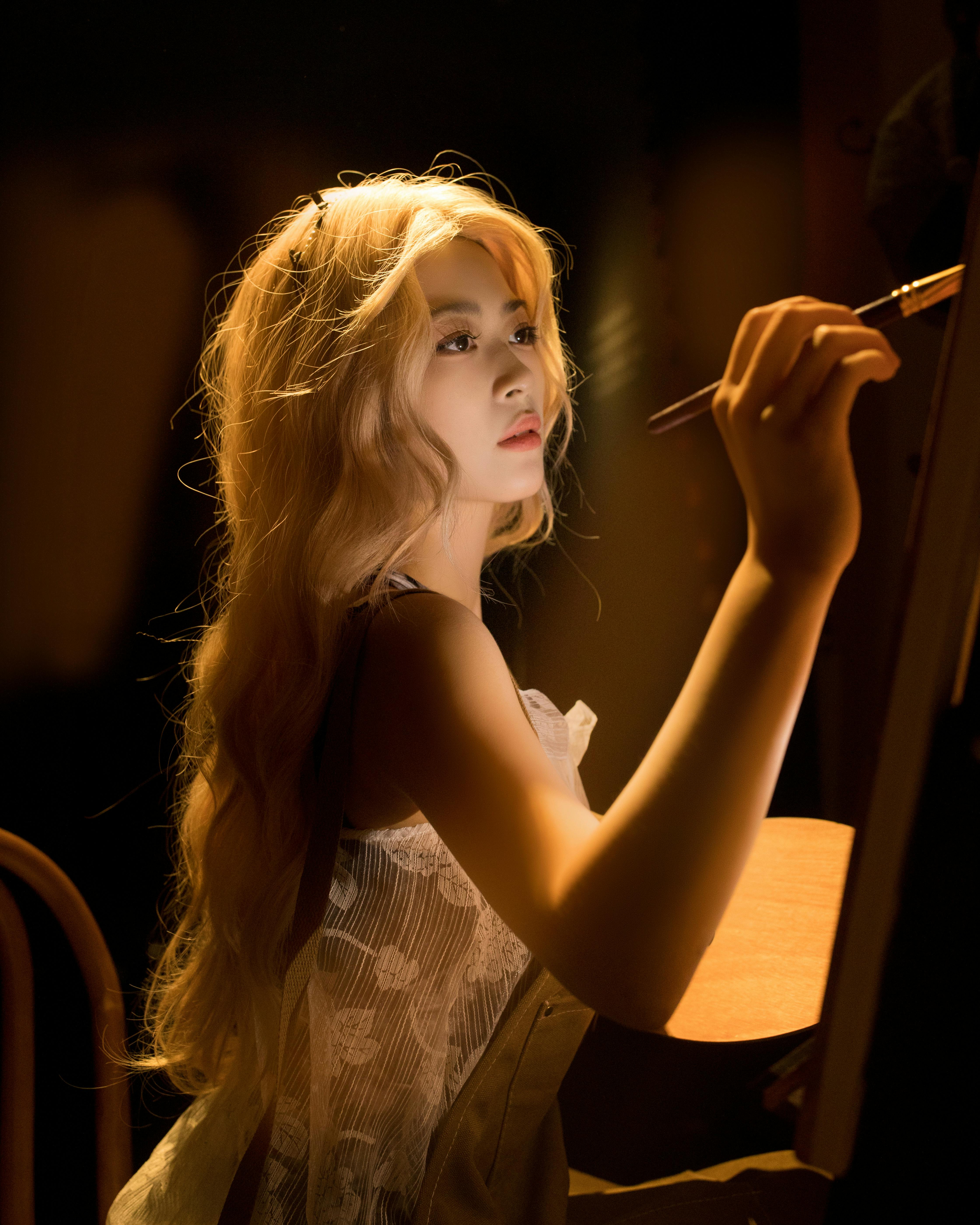 A focused artist painting on canvas with warm, soft lighting, creating an intimate scene.